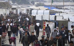 People walking next to tents with white bags of food.