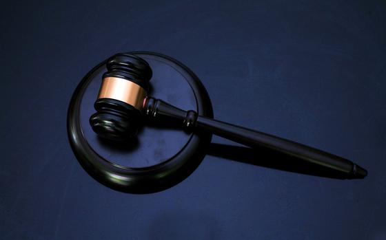 A black gavel sits against a block on a blue velvet backdrop.