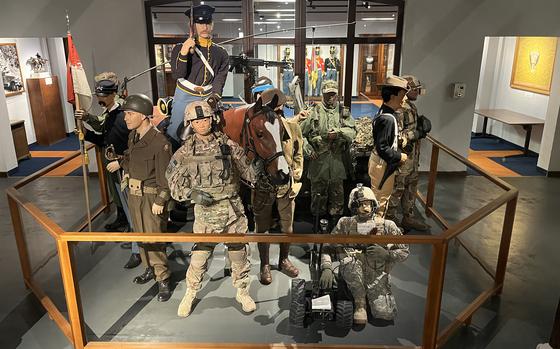Military uniforms are on display in a museum.