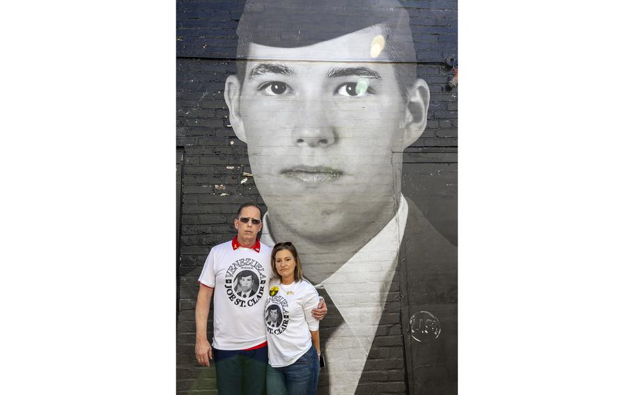 Two people standing in front of a mural on the side of a building.