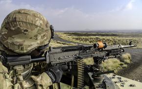An Army soldier prepares to fire a M249 squad automatic weapon light machine gun from a light medium tactical vehicle.